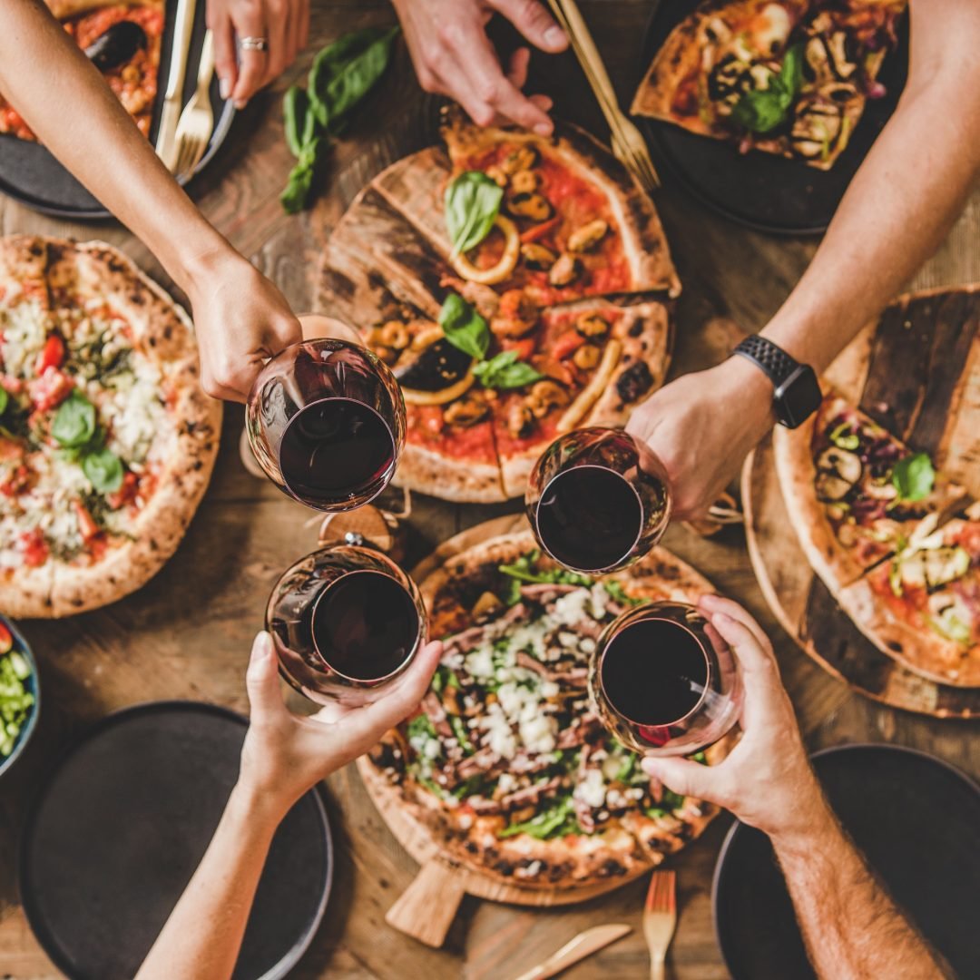 people-clinking-glasses-over-table-with-italian-pizza-square-crop.jpg